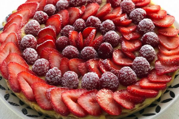 A visually stunning French tart with fresh strawberries and raspberries dusted with sugar.