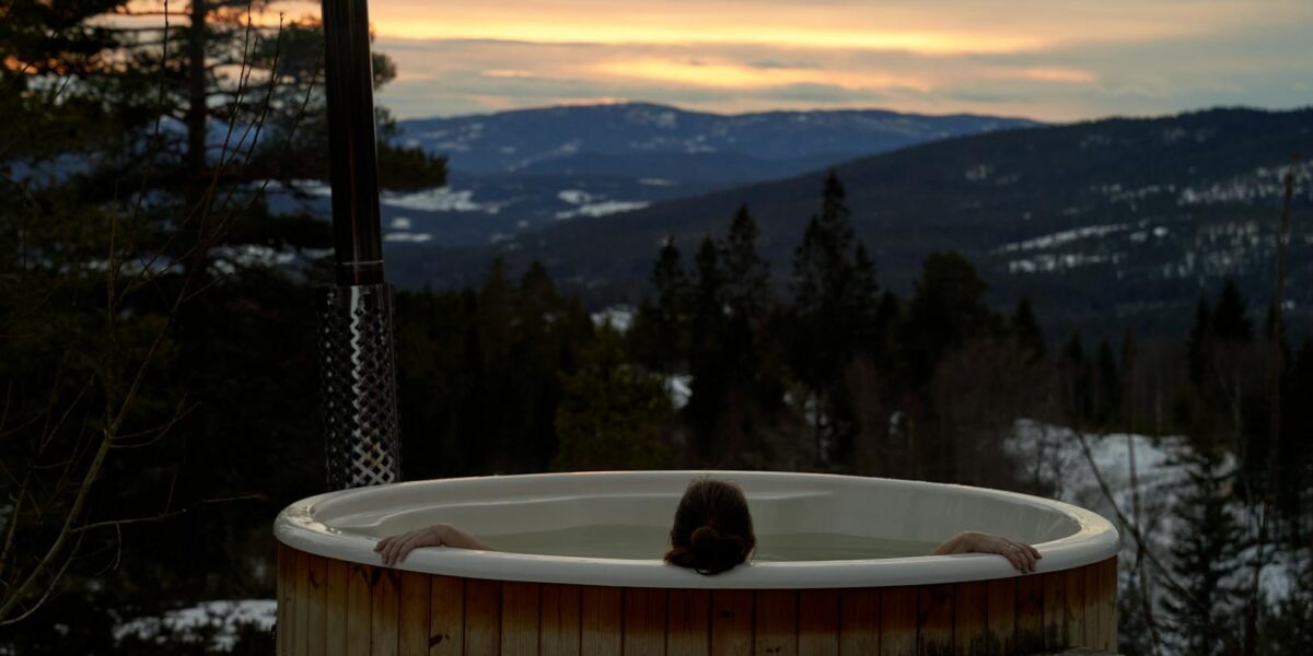 Cozy winter relaxation in a hot tub with stunning Norwegian mountain sunset views in Krøderen, Norway.