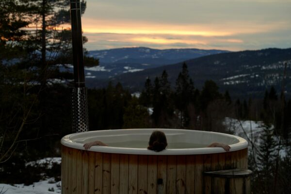 Cozy winter relaxation in a hot tub with stunning Norwegian mountain sunset views in Krøderen, Norway.