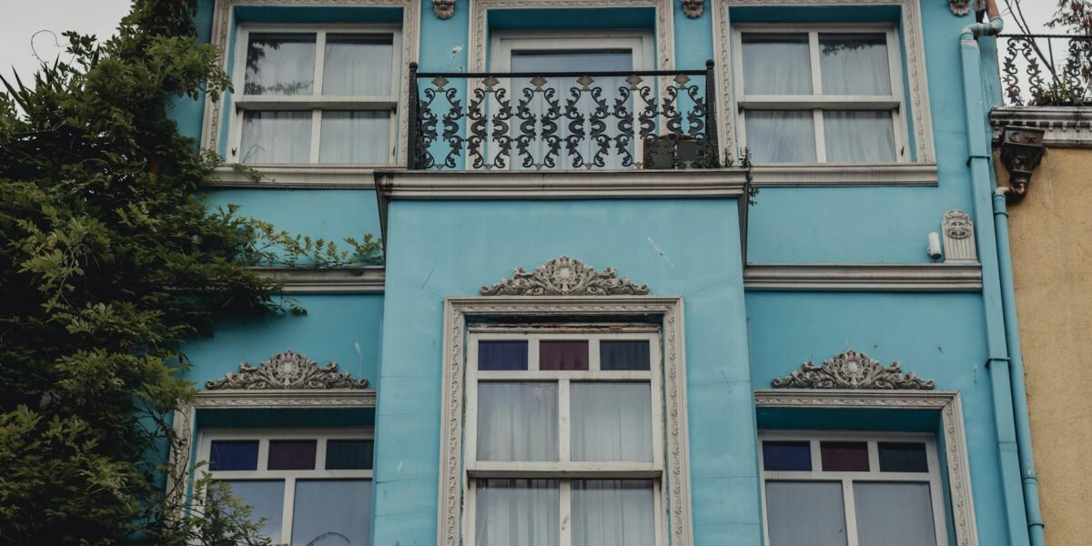 Captivating facade of a blue building with ornate details and lush greenery.