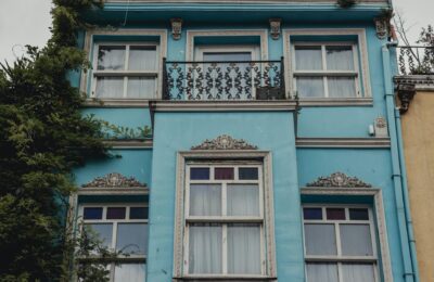 Captivating facade of a blue building with ornate details and lush greenery.