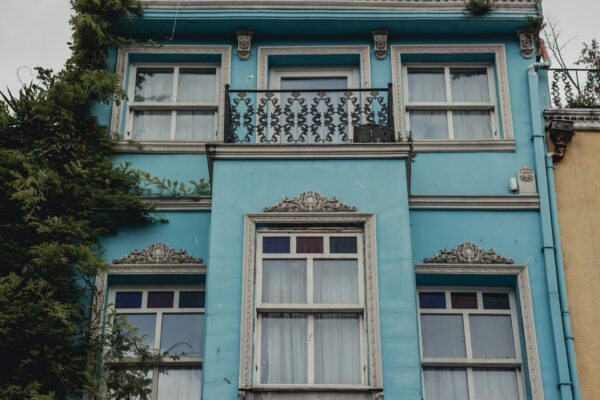 Captivating facade of a blue building with ornate details and lush greenery.