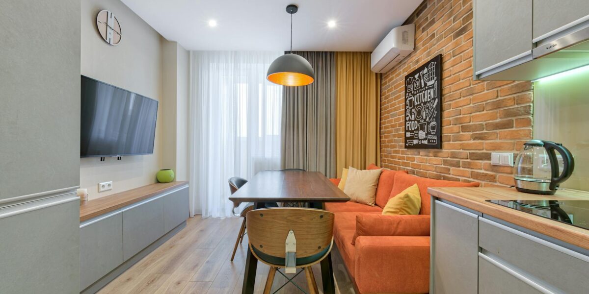 Stylish apartment interior with a brick wall, orange sofa, and wooden furniture.