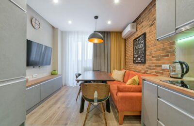 Stylish apartment interior with a brick wall, orange sofa, and wooden furniture.