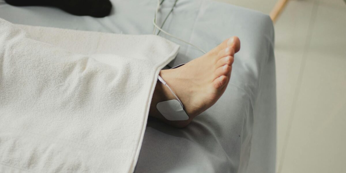 A close-up image of a bare foot with a medical electrode, suggesting a healthcare setting.