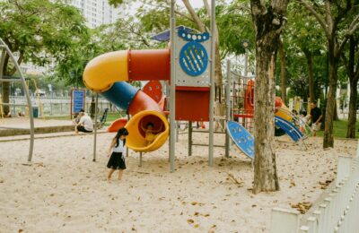 Kids enjoying colorful slides and play structures in an outdoor park playground.