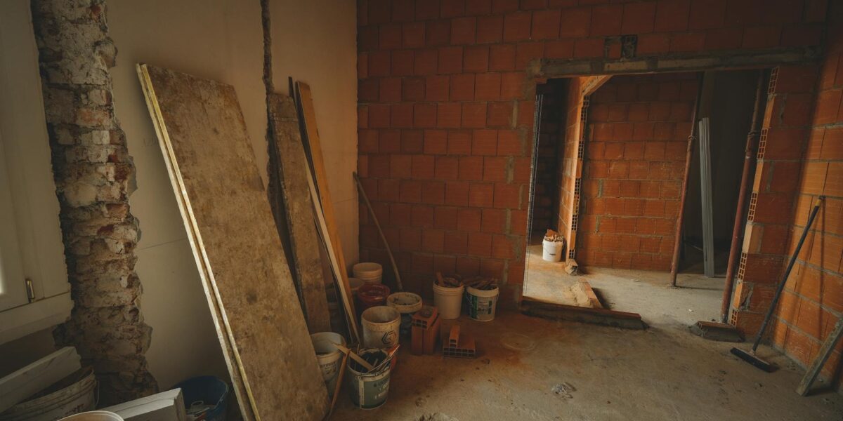 A red brick wall under construction with tools and materials scattered around in a renovation project.