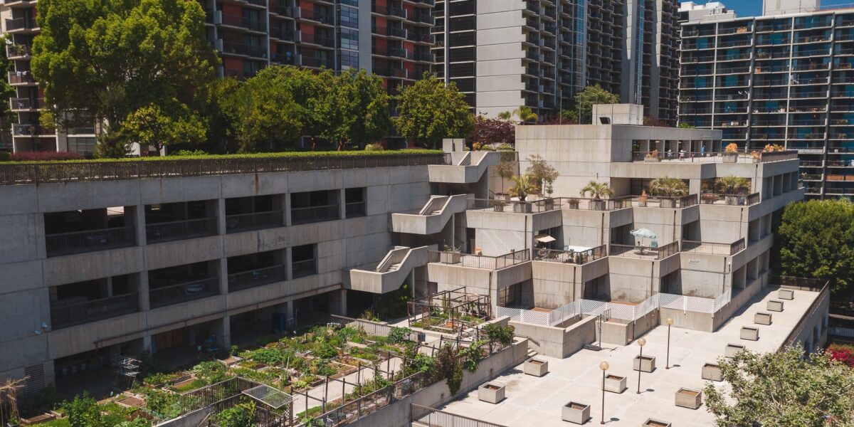 Aerial view of a rooftop garden on a concrete building in an urban area with high-rise apartments.