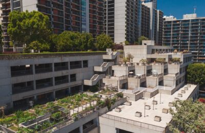 Aerial view of a rooftop garden on a concrete building in an urban area with high-rise apartments.