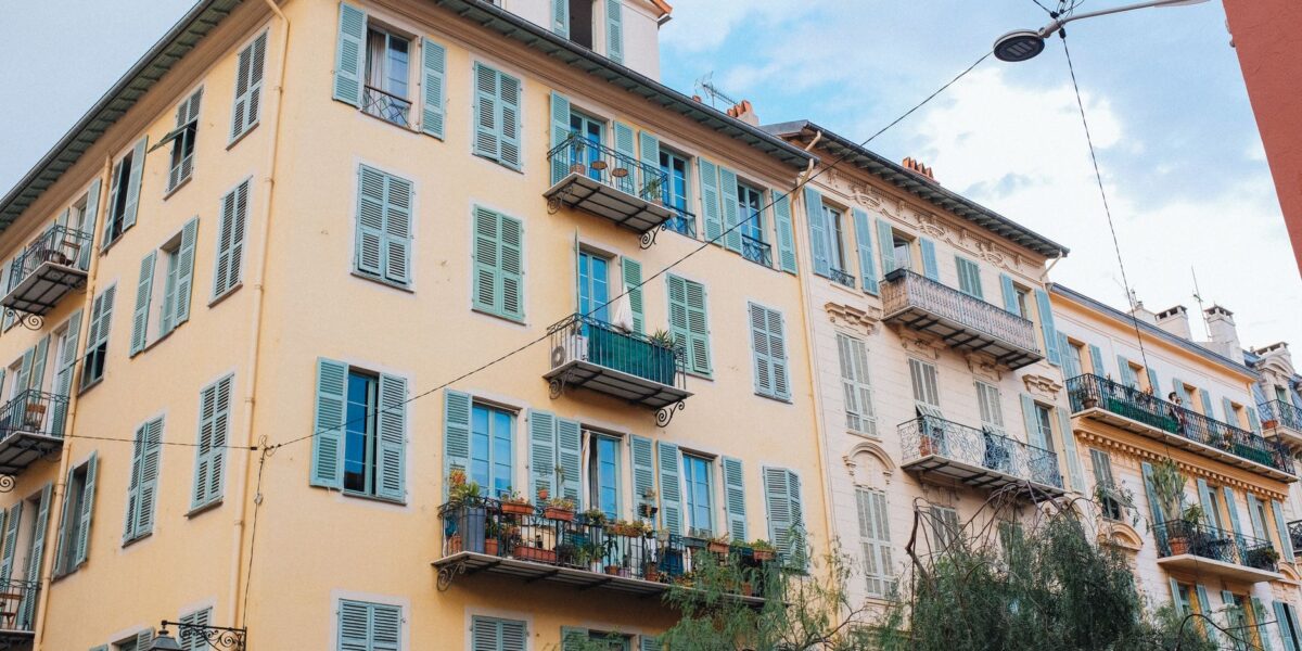 Colorful European apartment building with shutters and balconies against a clear sky.
