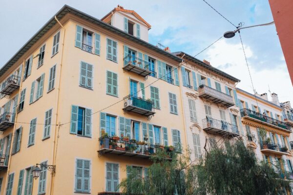 Colorful European apartment building with shutters and balconies against a clear sky.