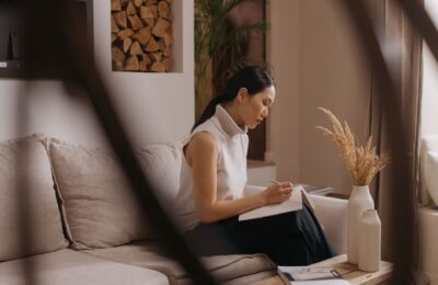 A woman sits on a sofa, taking notes in a Japandi styled living room.