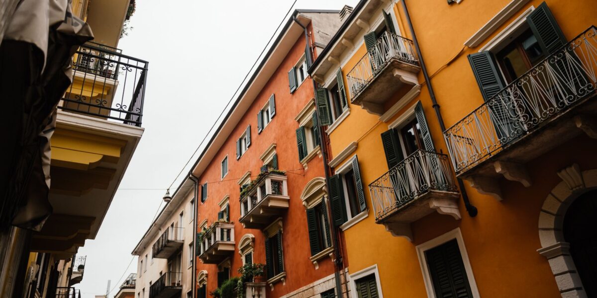 Charming narrow street with traditional Italian apartment facades featuring vibrant colors and balconies.