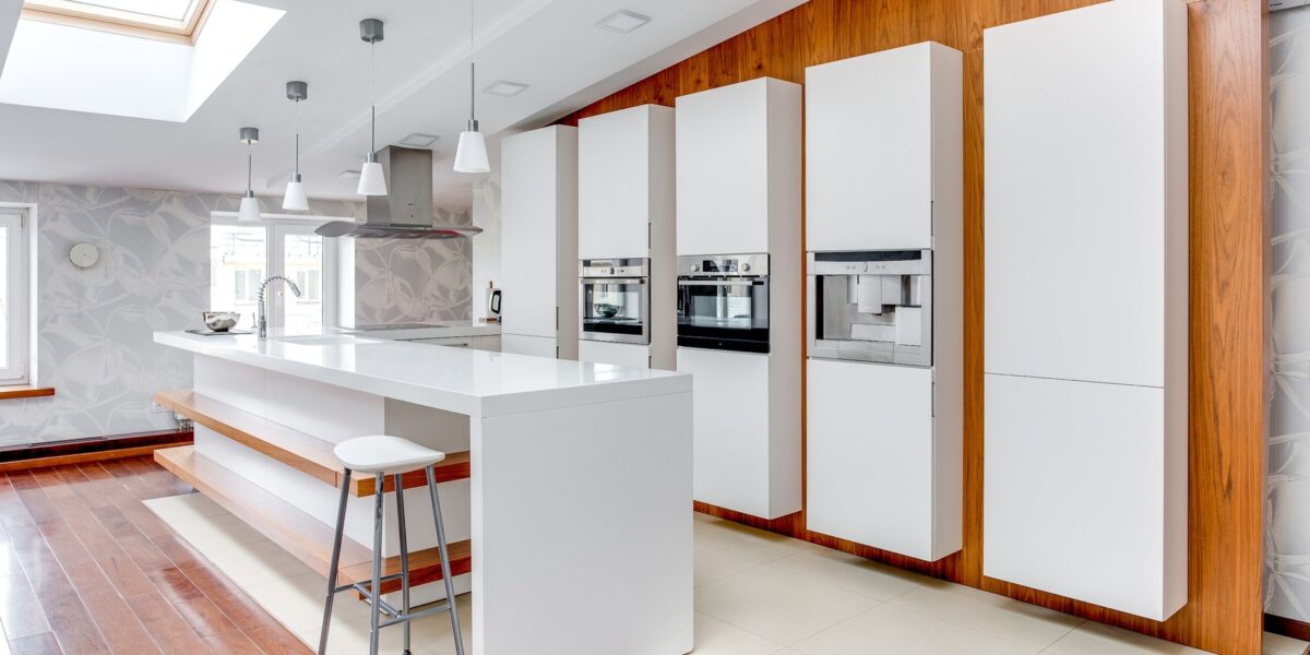 Sleek modern kitchen featuring white cabinets, wooden accents, and a spacious design highlighting minimalist aesthetics.