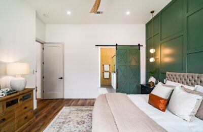 Beautiful modern bedroom with green accent wall and barn door leading to the bathroom.