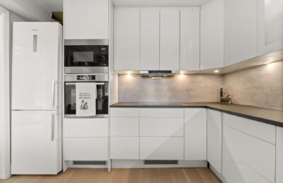 Sleek modern kitchen featuring white cabinetry, built-in appliances, and minimalist design.