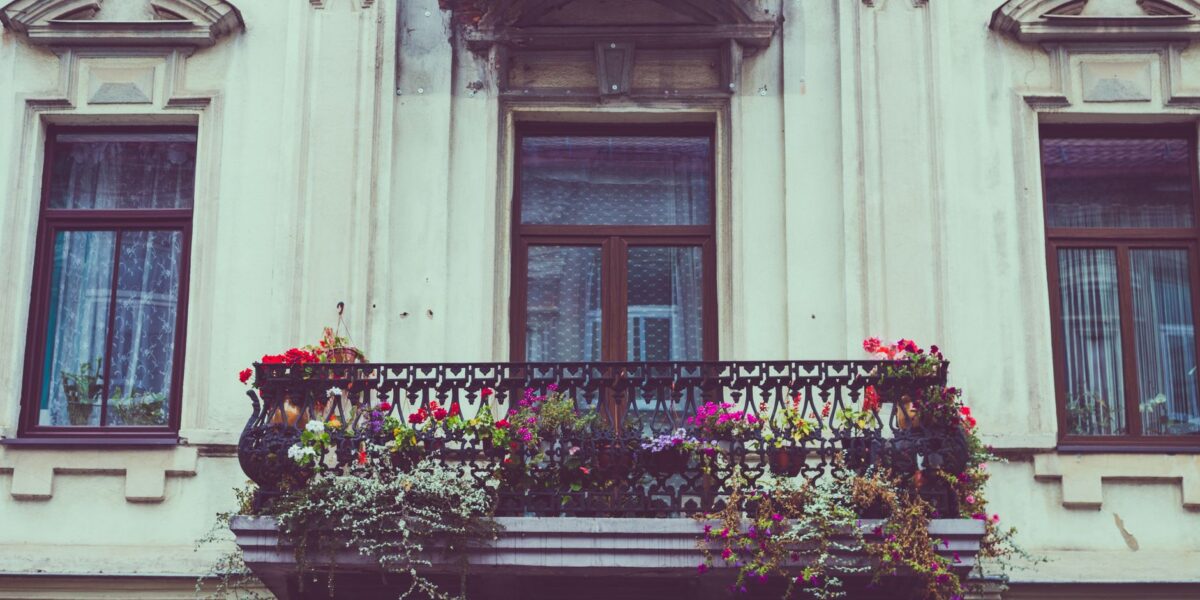 A beautiful vintage balcony adorned with colorful flowers and iron railing.