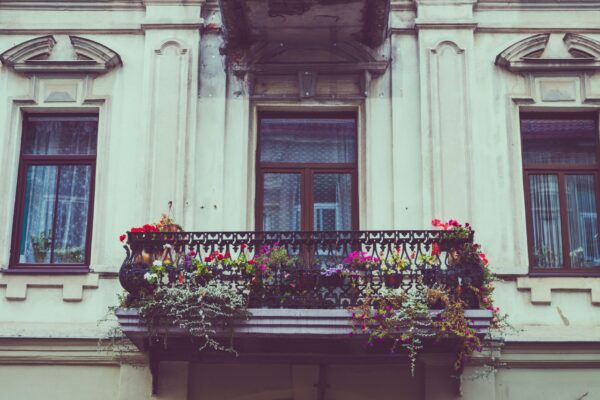 A beautiful vintage balcony adorned with colorful flowers and iron railing.