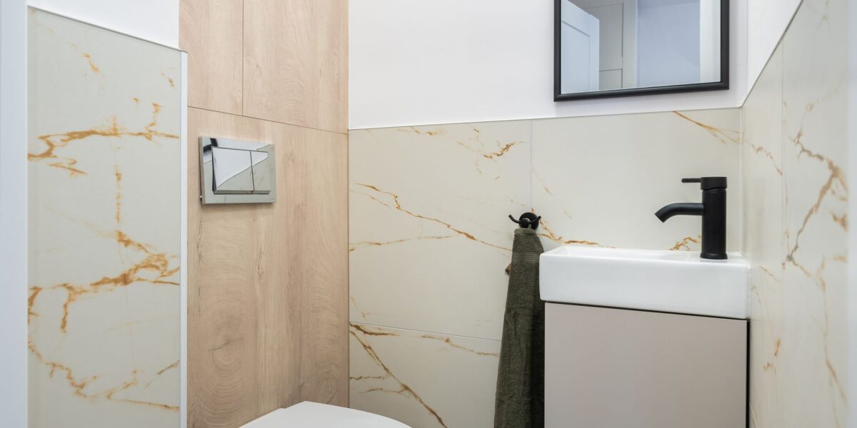 Clean and stylish modern bathroom with marble tiles and a small sink.