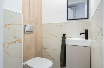Clean and stylish modern bathroom with marble tiles and a small sink.