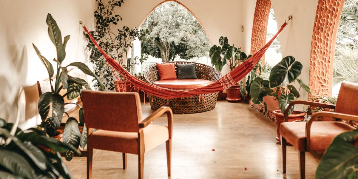 Inviting indoor patio with hammock, rustic chairs, and lush plants showcasing modern design.