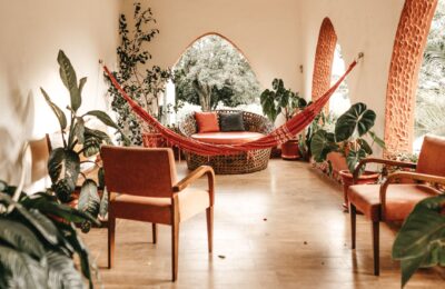 Inviting indoor patio with hammock, rustic chairs, and lush plants showcasing modern design.