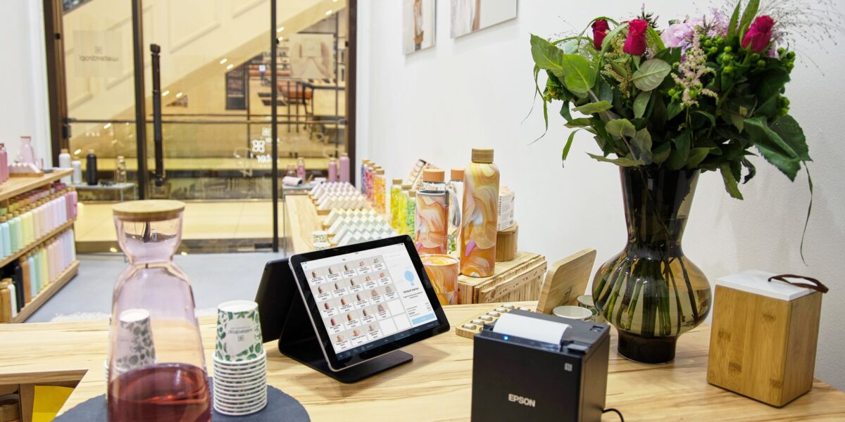 A stylish store checkout counter featuring a floral bouquet and digital payment system.