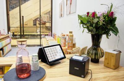 A stylish store checkout counter featuring a floral bouquet and digital payment system.