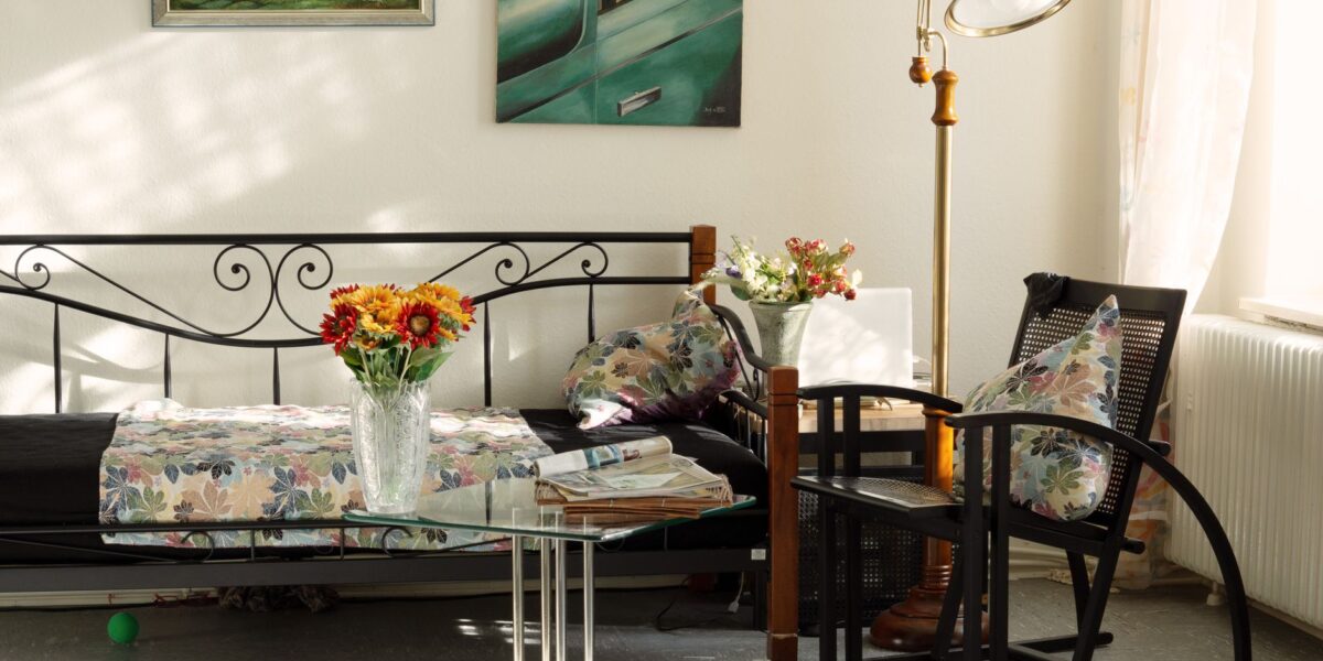Charming living room featuring artistic decor, floral pillows, and cozy seating in natural light.