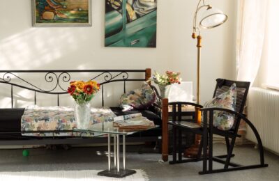 Charming living room featuring artistic decor, floral pillows, and cozy seating in natural light.
