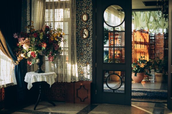 A vintage-styled room with a colorful floral bouquet and ornate door, bathed in warm sunlight.