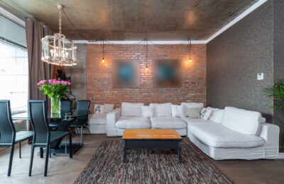 Stylish living room featuring industrial design with brick wall, white sofa, and chic chandelier.