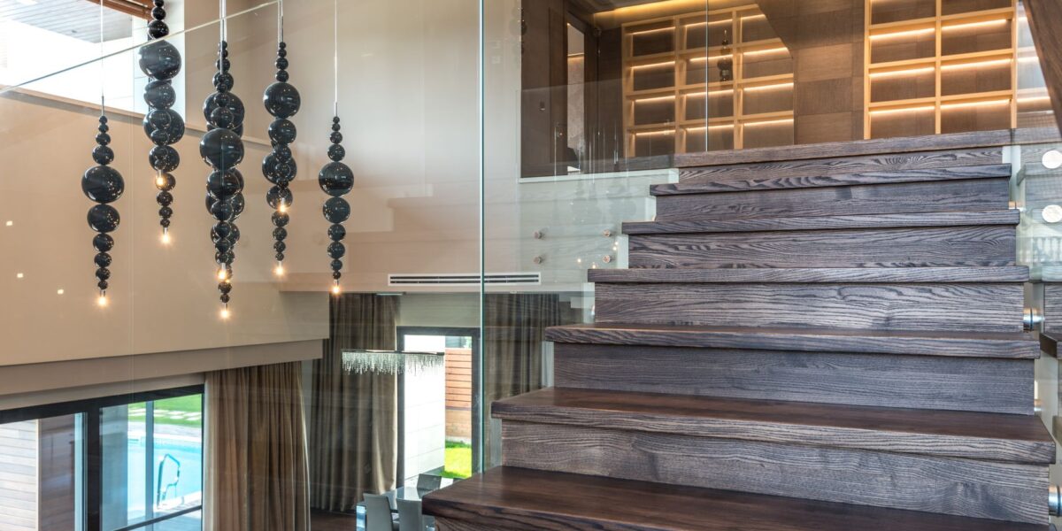 Elegant interior design featuring a wooden staircase with glass railing and artistic lighting.