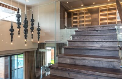 Elegant interior design featuring a wooden staircase with glass railing and artistic lighting.