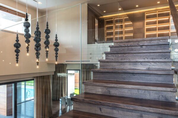 Elegant interior design featuring a wooden staircase with glass railing and artistic lighting.