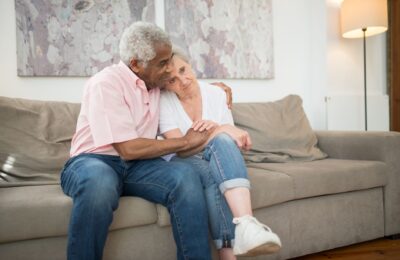 Senior couple embracing warmly on a sofa at home, showcasing love and togetherness.