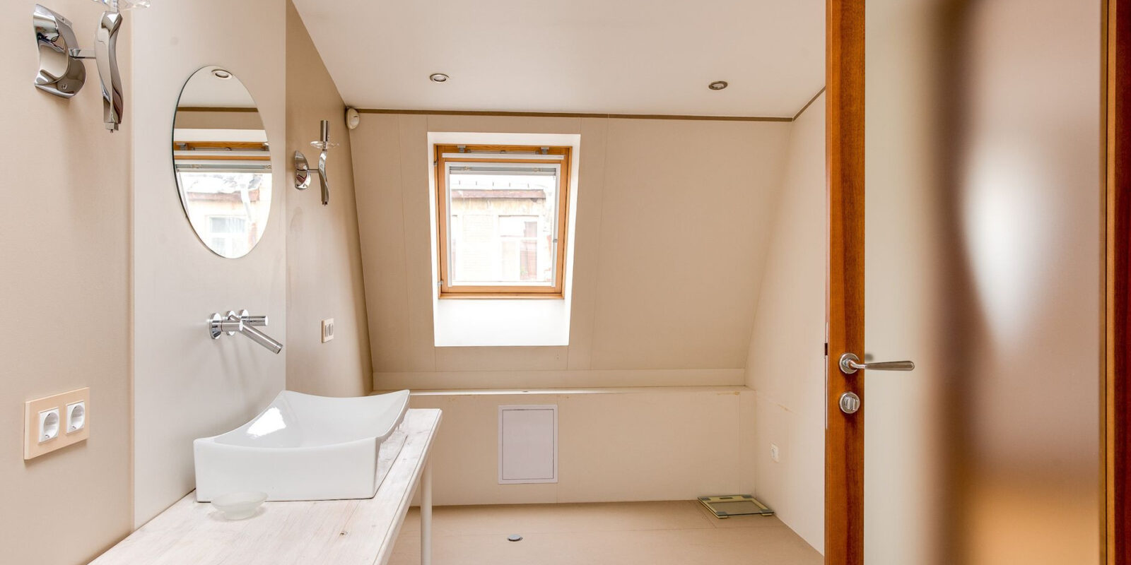 A stylish and spacious attic bathroom featuring a minimalist design, skylight, and modern fixtures.