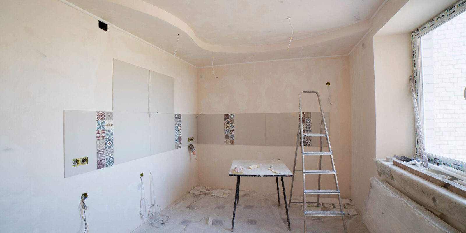 Spacious kitchen under renovation with ladder and tools, showcasing a fresh new design.