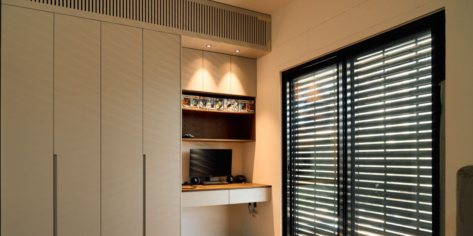 A minimalist home office with sleek design and ample natural lighting through large blinds.