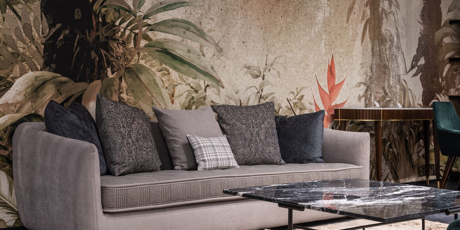 Comfortable sofa with pillows placed at wall with painted leaves in modern spacious room with table on rug at home