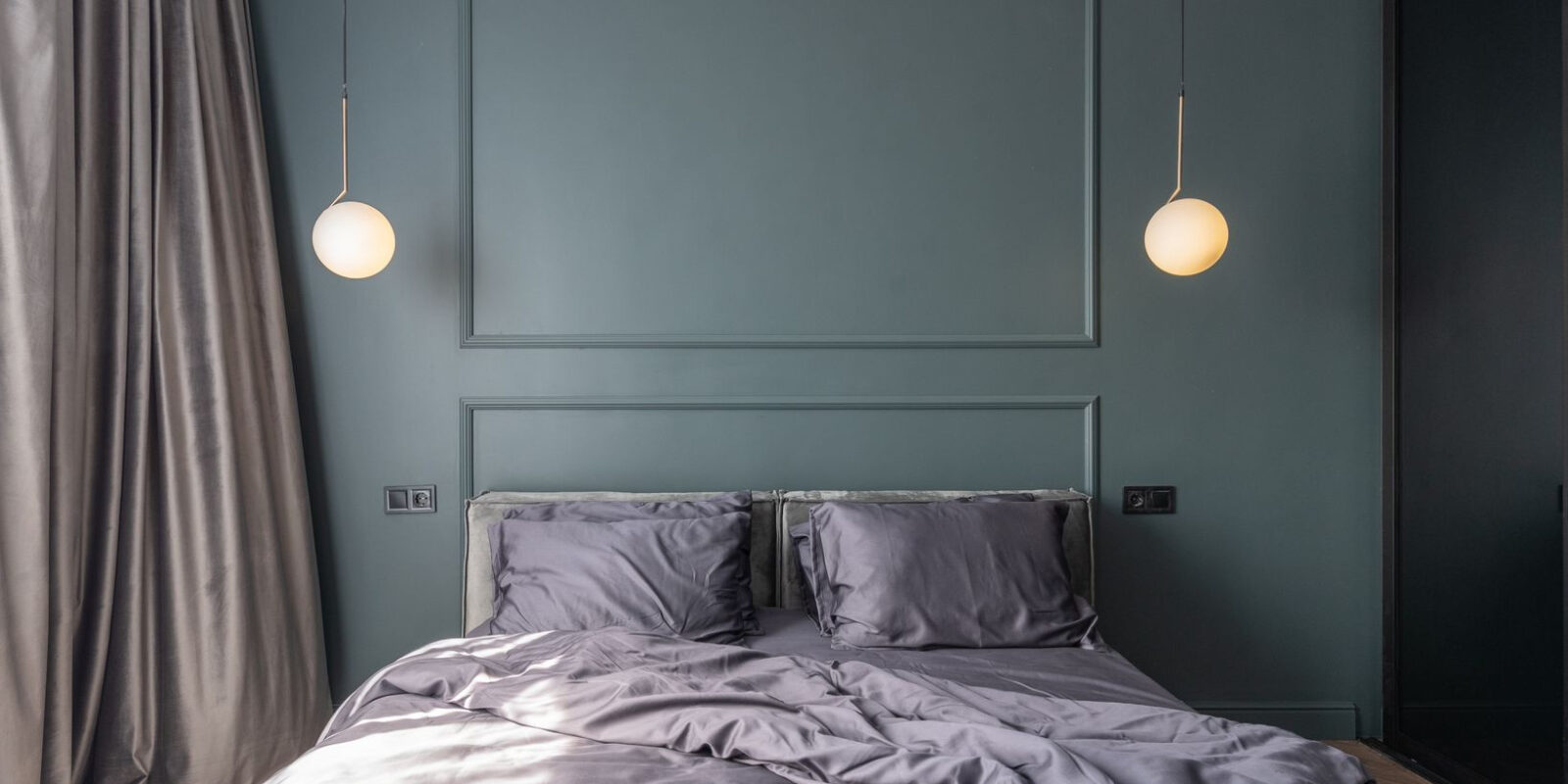 Interior design of modern bedroom with unmade bed under luminous lamps at sunlight