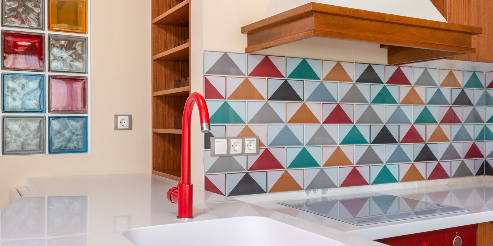 Interior of stylish kitchen with colorful tile and red faucet in modern apartment