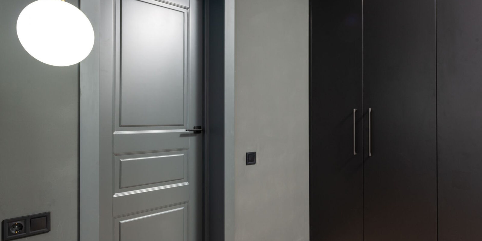 Stylish interior with a minimalist wardrobe, grey door, and modern lighting fixture.