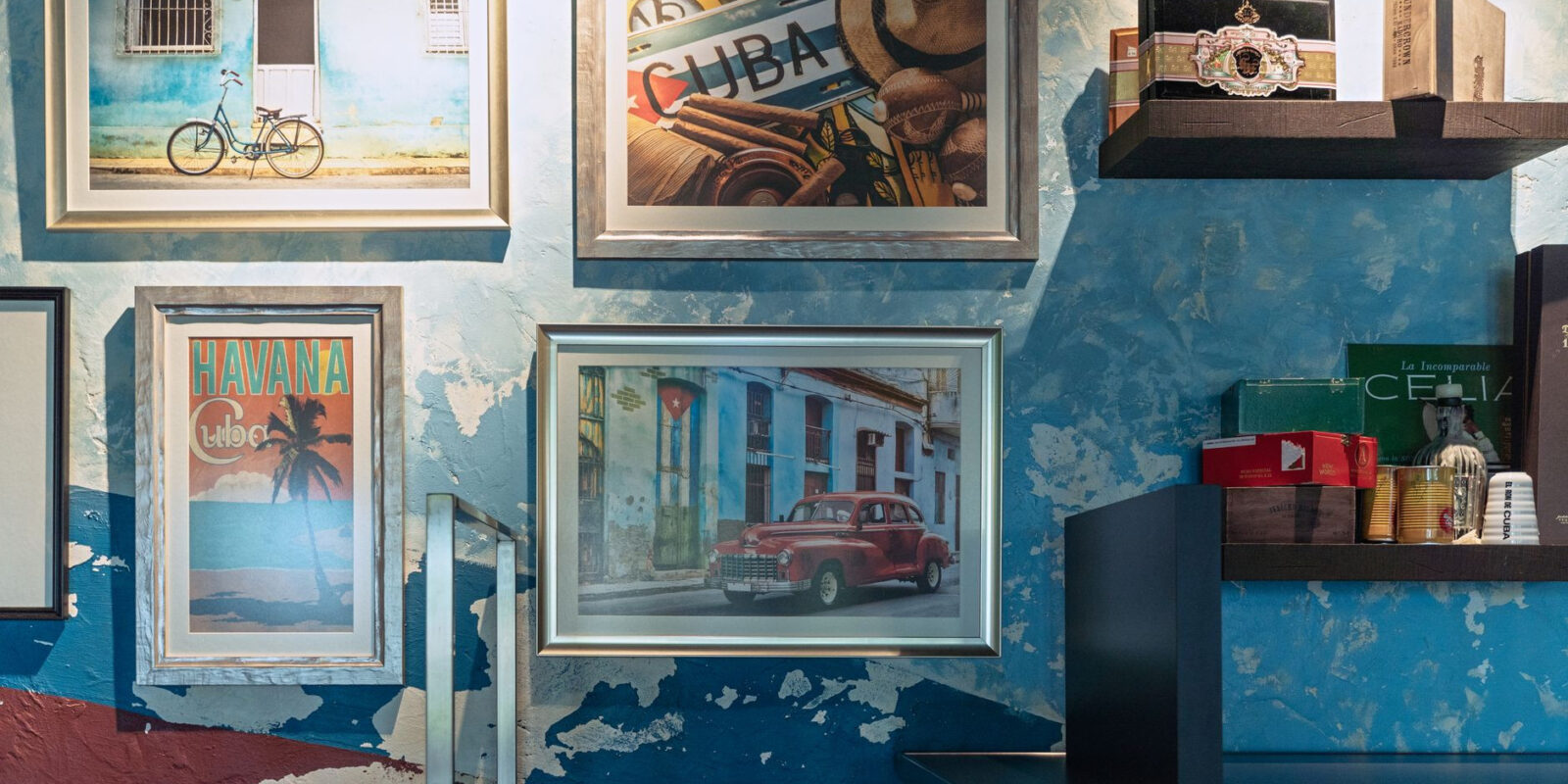 Cuban-themed framed art and decor on a textured blue wall for a vibrant interior look.