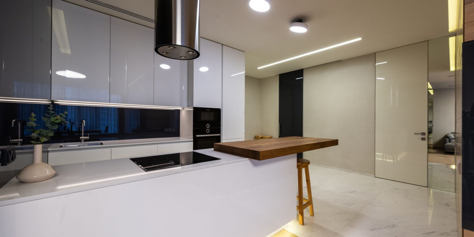 Modern kitchen interior with counter and appliances and glossy cabinets under shining lamps