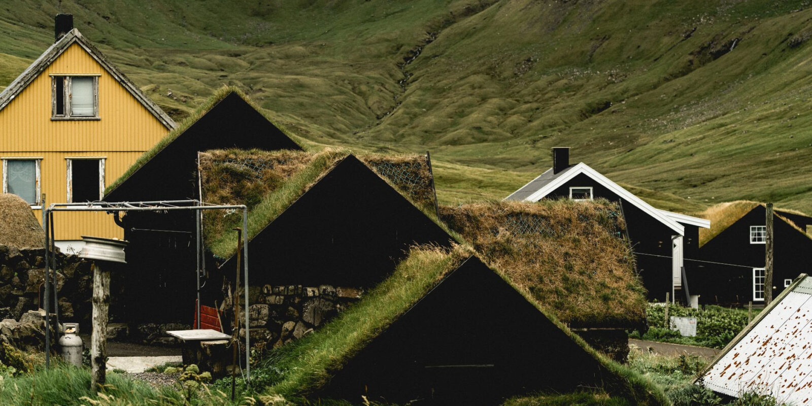 Traditional village with turf-roofed houses set in a lush valley landscape.