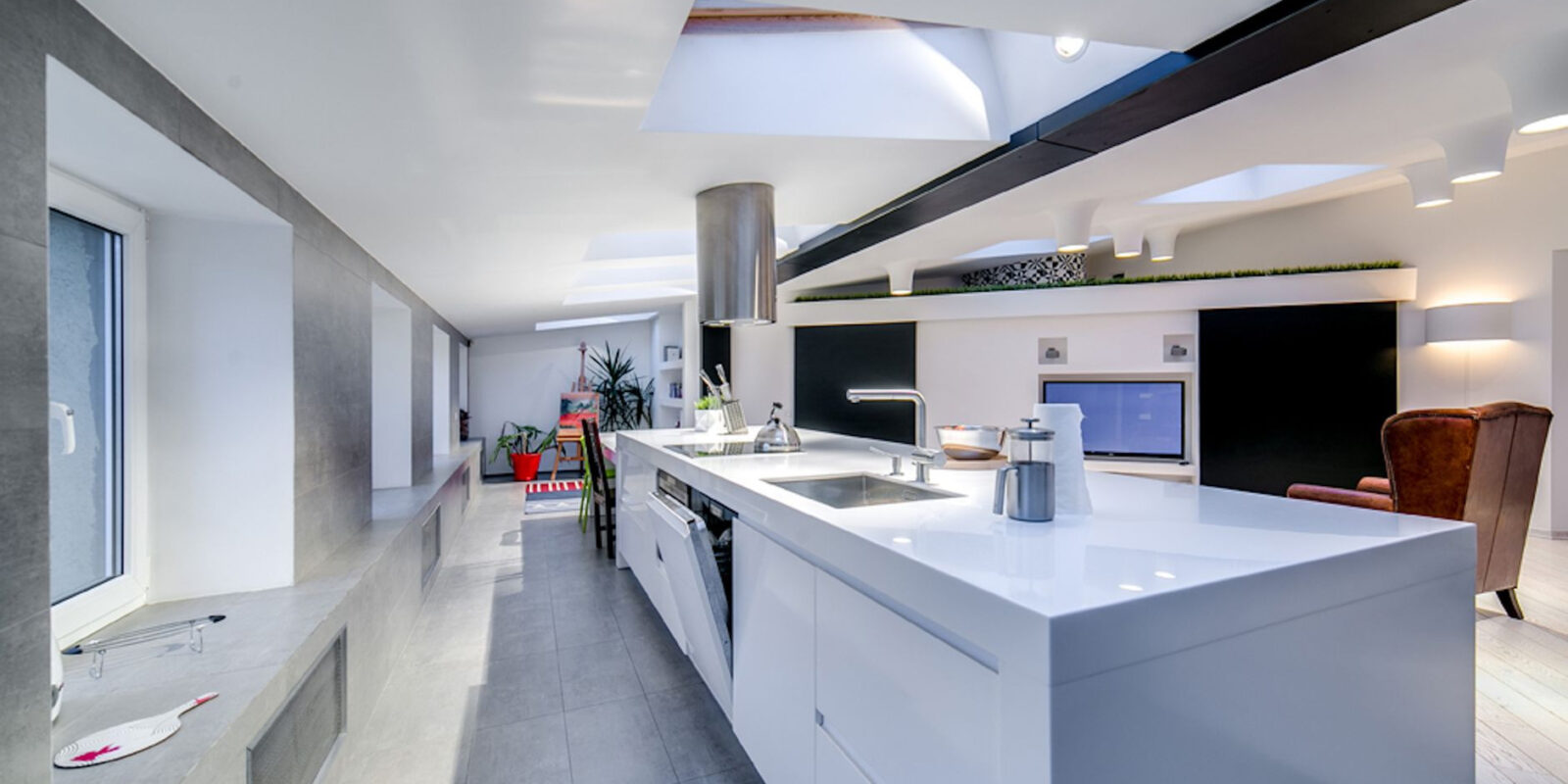 Bright and spacious modern kitchen interior with skylights and sleek design elements.