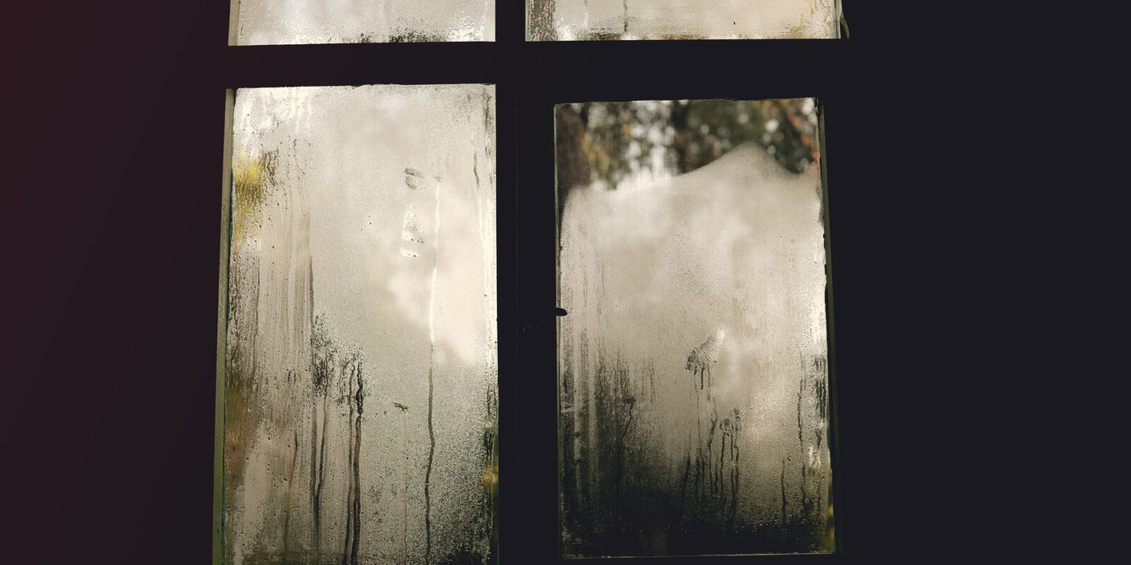 A foggy window pane with condensation, creating an abstract natural scene.